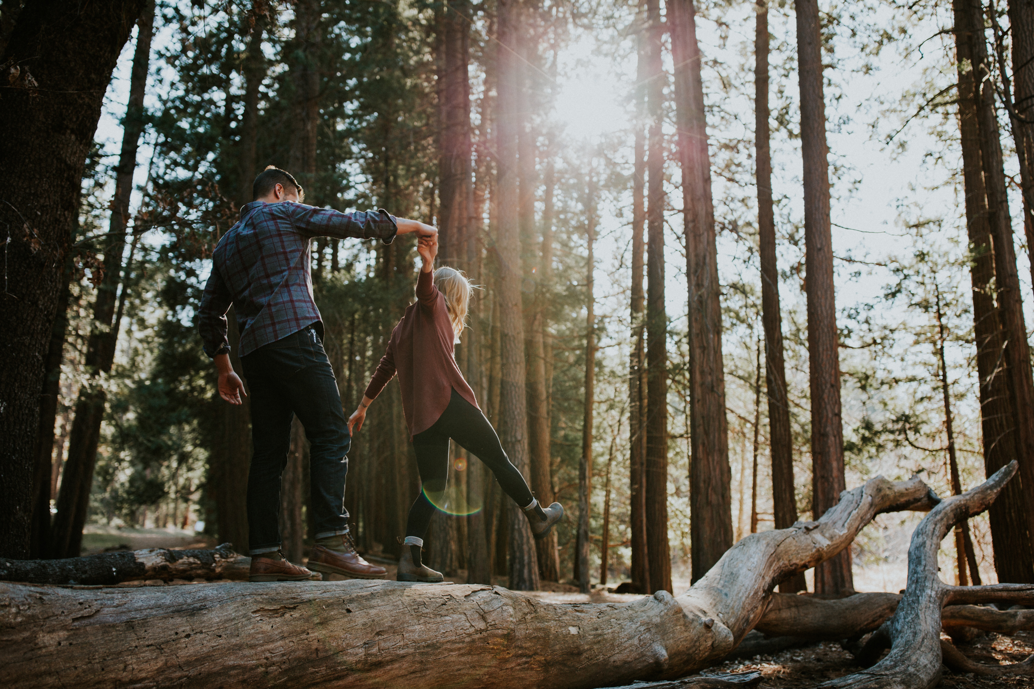 young couple walk along fallen log in Yosemite valley