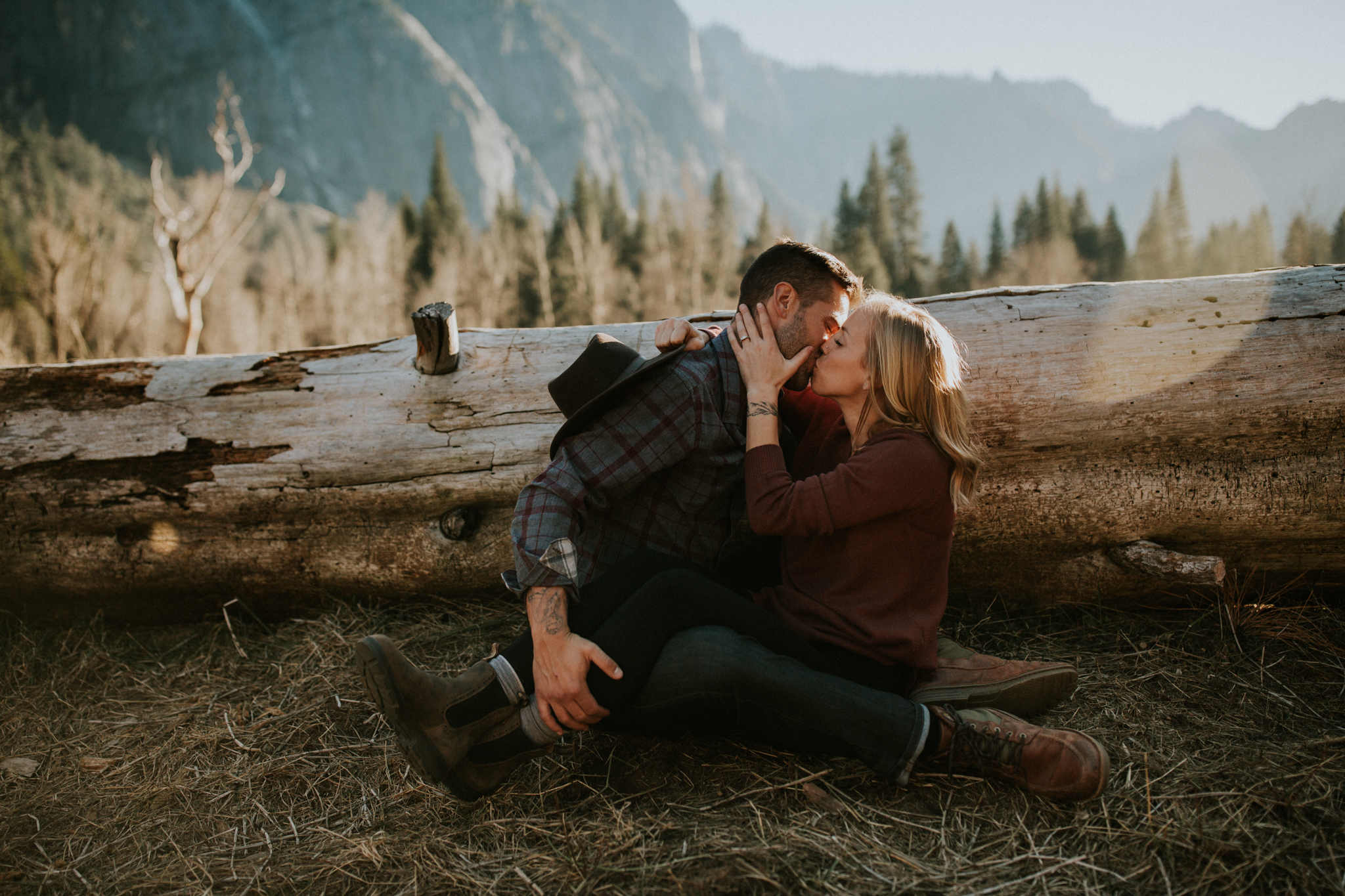 young couple kiss in Yosemite valley with mountains in distance