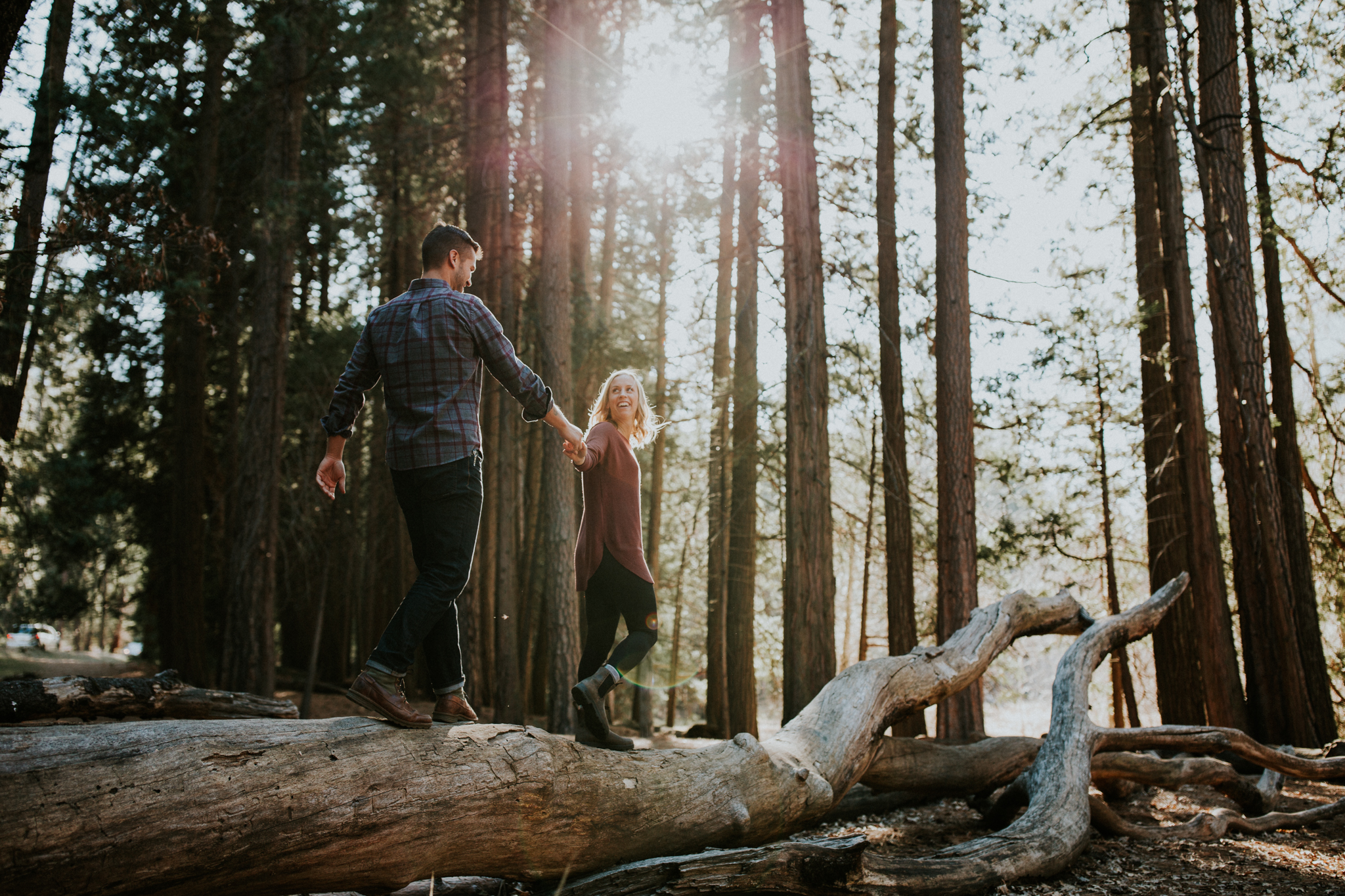 young couple walk along fallen log at Yosemite National Park