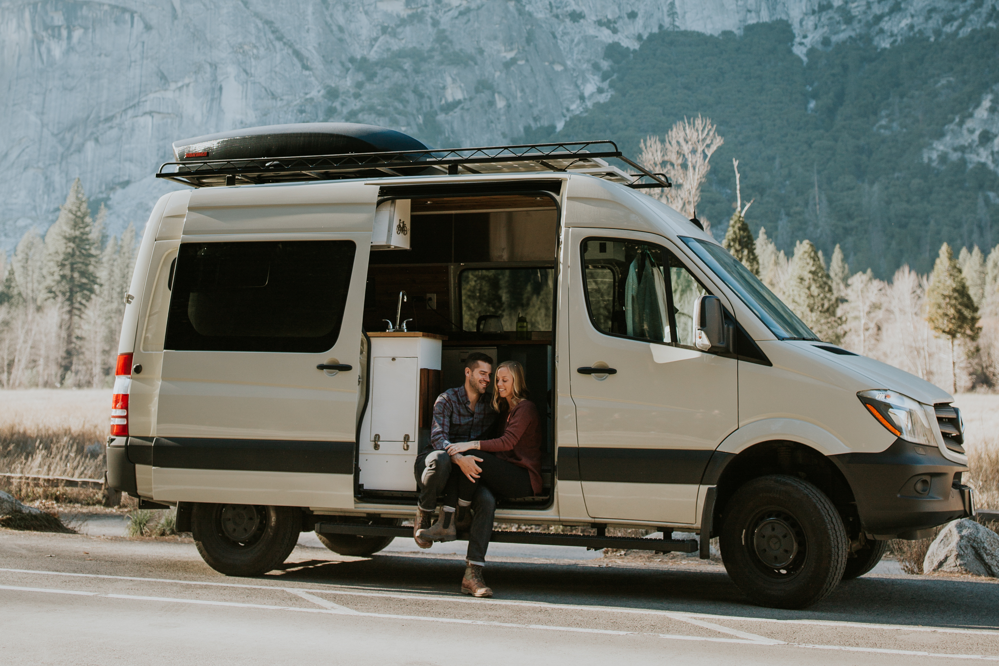 couple sit in old VW van parked on side of quiet road