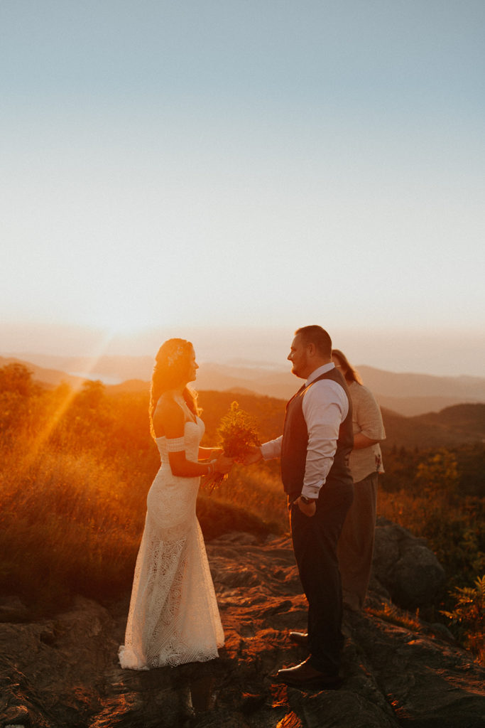 Man and woman being married on top of a mountain during sunrise