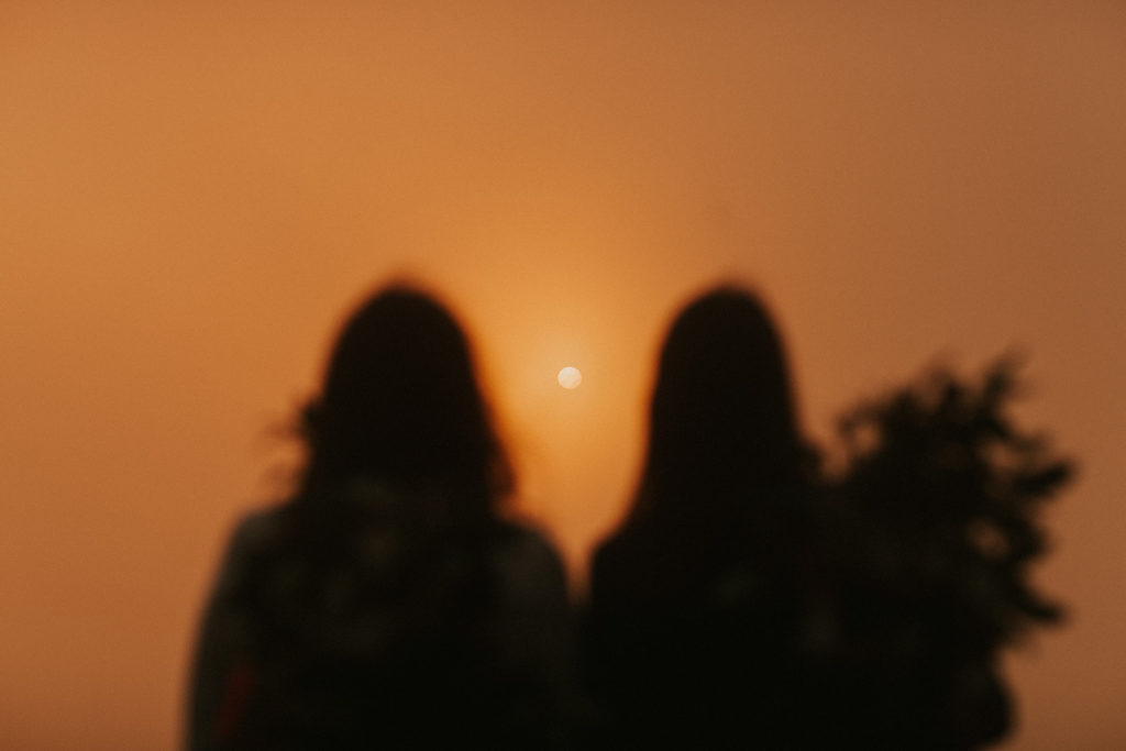 couple gazing out into an orange sunrise
