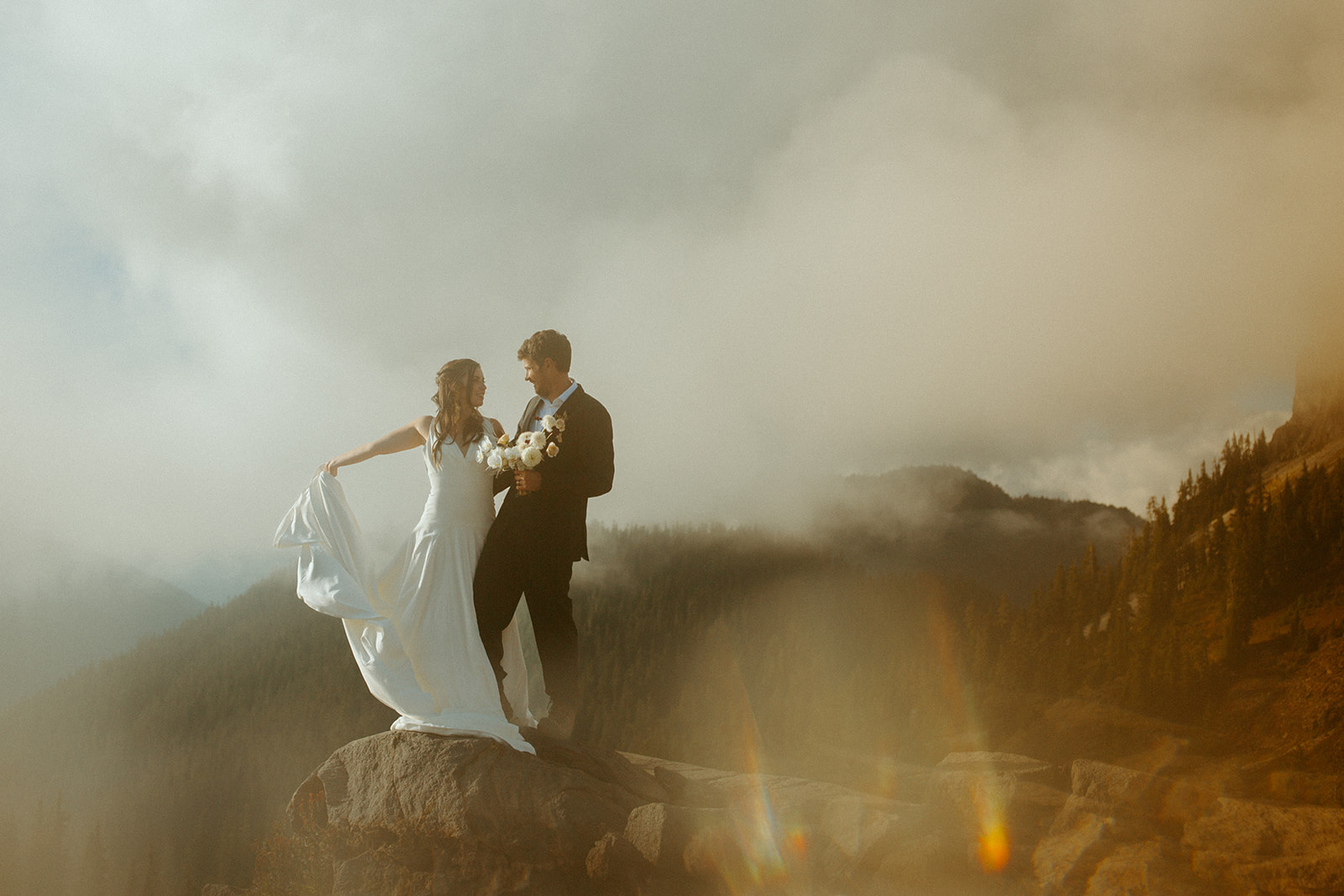 Couple elope in a national park with fog hovering over the mountains in the background.